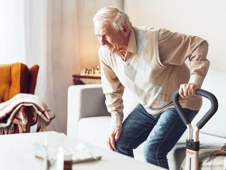 Äldre man reser sig upp från soffa med hjälp av Let’s Get Up uppresningsstöd.